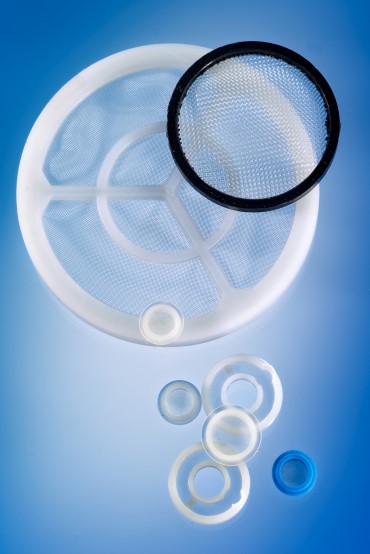 A selection of plastic moulded mesh filters, circular in shape, on a blue background